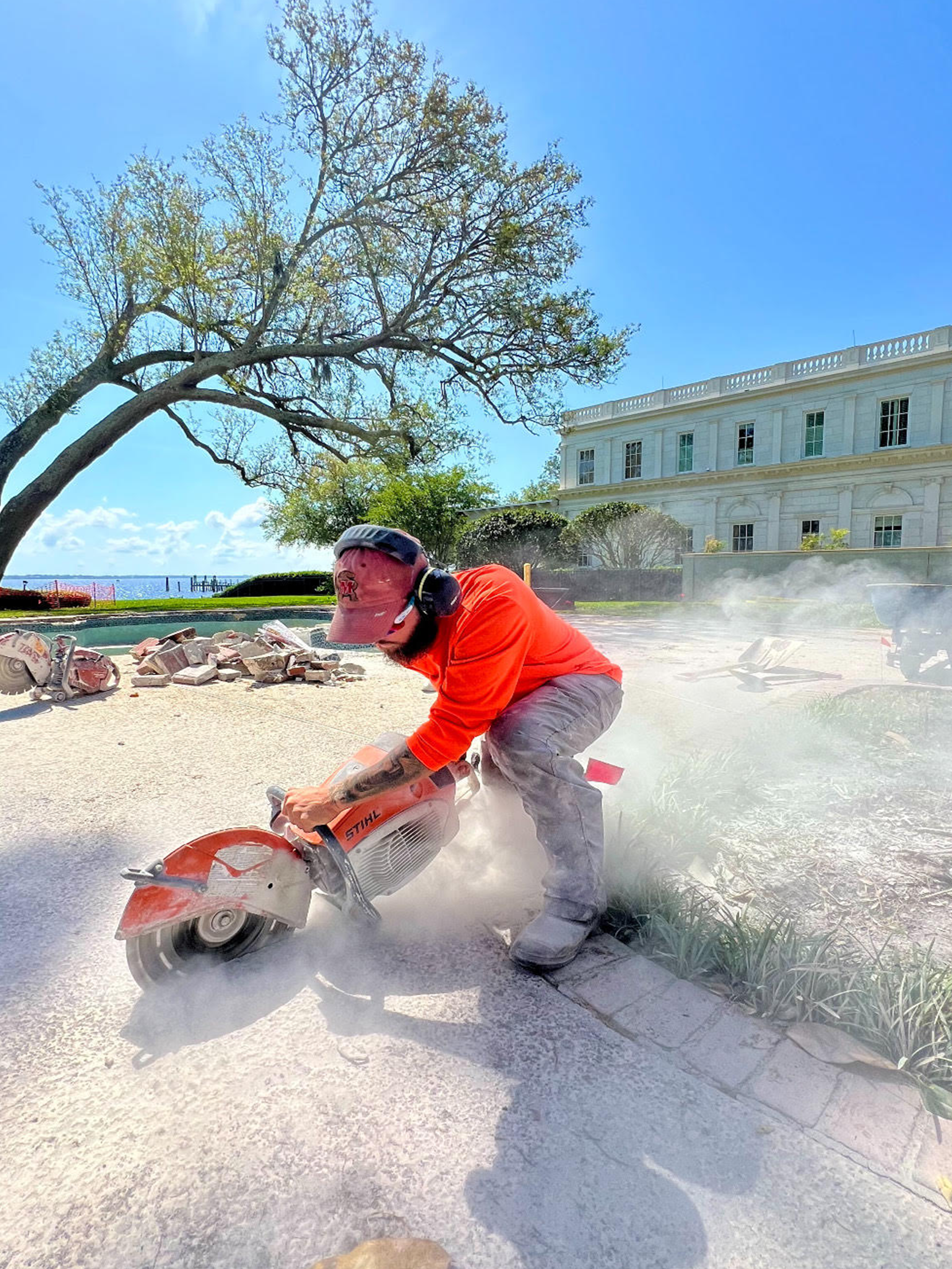 ERE CARE crew member cutting concrete during a pool-deck hardscape demolition job in Palm Coast