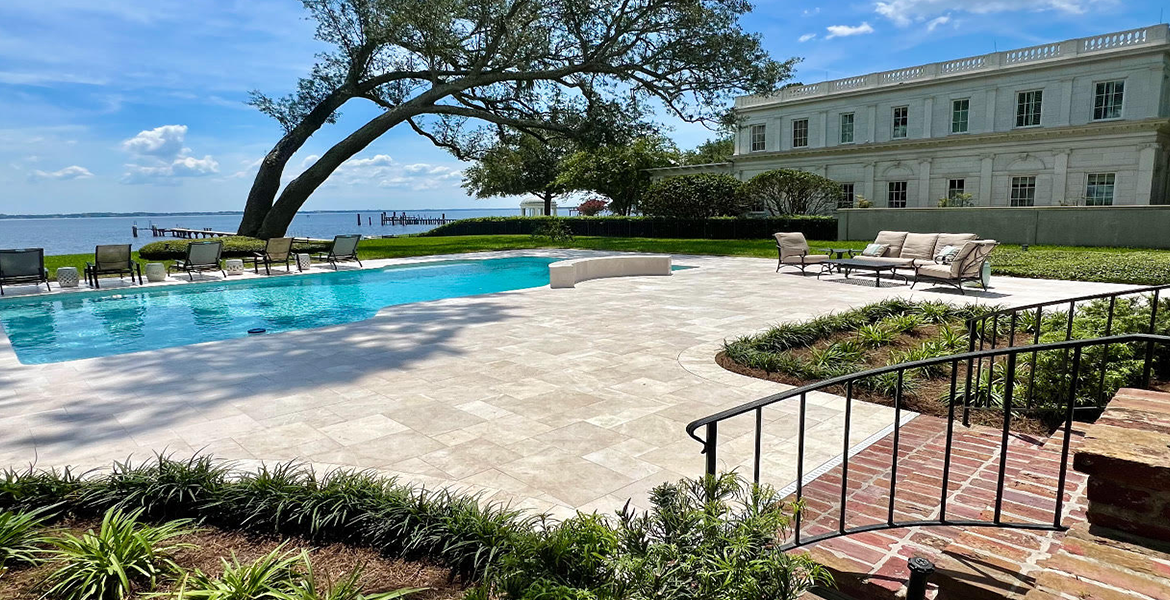 Finished paver pool deck and landscaping beside a waterfront home in Palm Coast