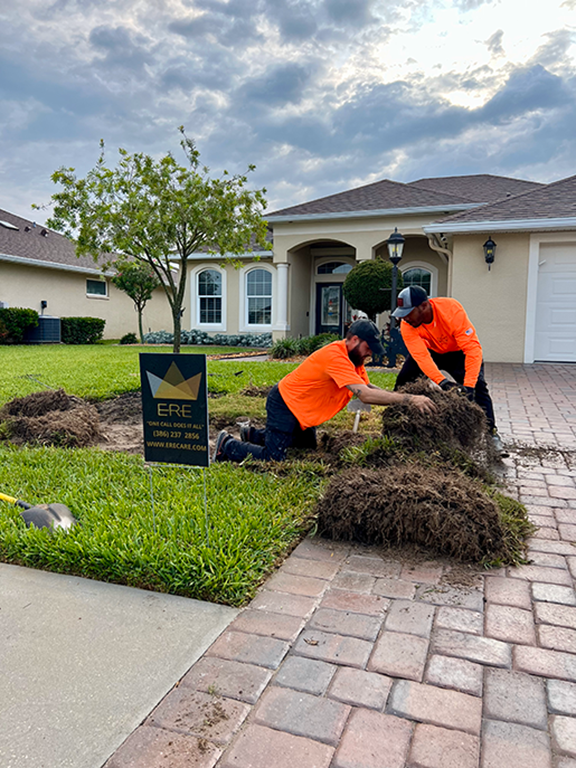 Two ERE CARE crew members installing fresh sod in front of a Palm Coast home, with an ERE Care yard sign